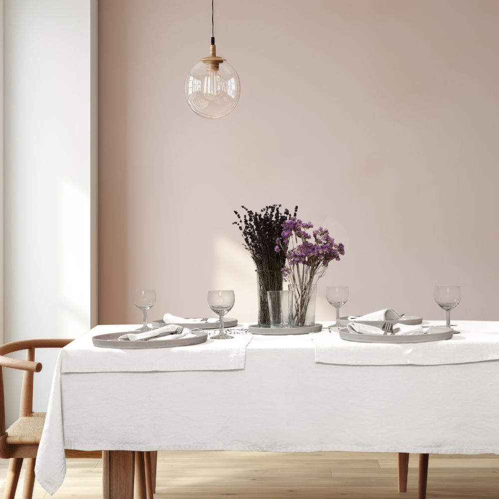 Gedeckter Esstisch mit weißer Leinen Tischdecke, Tellern, Servietten und Trockenblumen