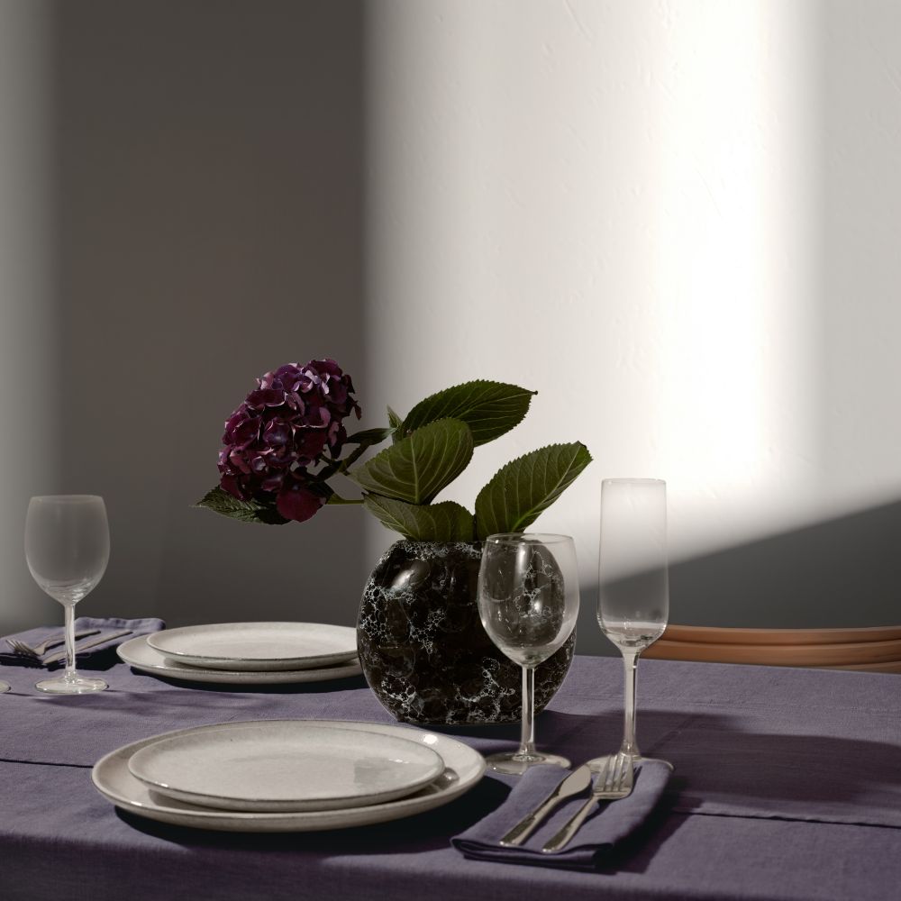 Gedeckter Tisch mit Leinen in Dunkelgrau, Hortensie in Vase, Teller und Gläsern